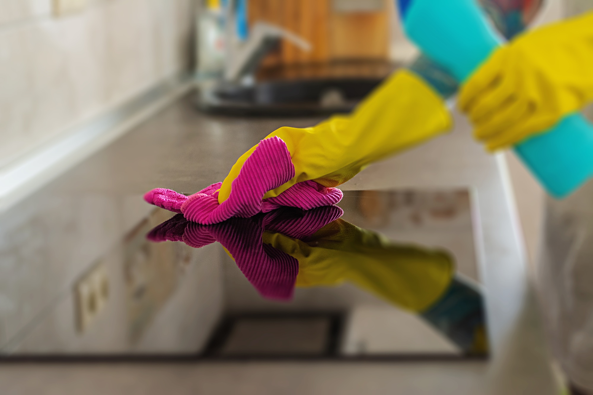 Woman in protective gloves wiping dust using cleaning spray and duster. Cleaning service concept.